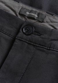 Pantaloni negri din bumbac cu o textură netedă, prevăzuți cu închidere cu buton și un eticheta cu inscripția "Matinique" în font alb.
