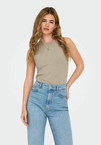 Haut sans manches beige avec un col rond, texture côtelée, associé à un jean bleu clair taille haute avec fermeture à bouton et poches.