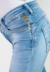 Lichtblauwe denim jeans met een slim fit, voorzien van gouden hardware accenten en een zichtbaar merkembleem op de tailleband.