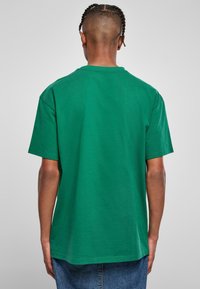 Zelené bavlněné tričko s krátkým rukávem, volný střih a kulatým výstřihem. Hladká textura a jednobarevný design.