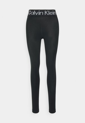 Black leggings made of stretchy material with a wide elastic waistband featuring the "Calvin Klein" logo in white. Fitted design, no patterns.