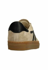 Beige suède sneaker met een zwarte leren hielaccent, gumrubberen zool en gestikte zwarte strepen aan de zijkant. Over het algemeen een gladde textuur.