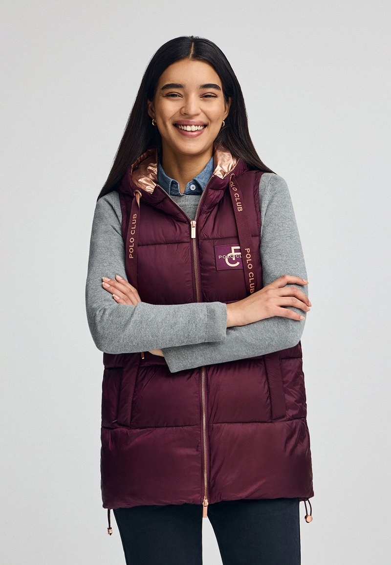 Maroon pufferväst med huva, med en glänsande roséguldsfoder, dragkedjestängning och "Polo Club"-logotyp på remmarna och bröstet.