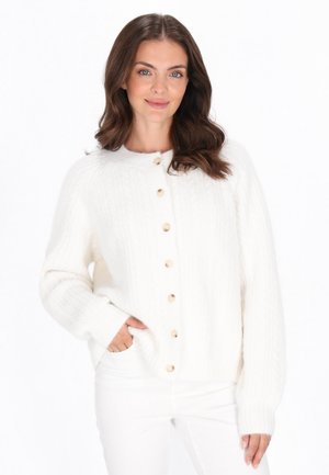 Valkoinen neulecardigan, jossa on ribattu pinta, isoja beigejä nappeja, pyöreä pääntie ja pitkät hihat.