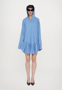 Abito blu con bottoni, orlo svasato e maniche lunghe, dotato di cappuccio. Tessuto liscio con un sottile motivo a quadri.