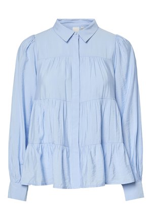 Lyseblå bluse med lange ermer, lagdelte volanger, knappestolpe foran, spiss krage og rynkede stoffdetaljer på ermer og kropp.