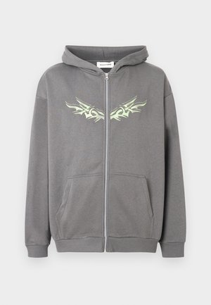 Felpa grigia con zip e cappuccio, tasche frontali, polsini e orlo a costine, con un motivo tribale simmetrico verde chiaro sul petto.
