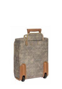 Valise à roulettes souple en matériau beige texturé avec des accents en caoutchouc marron, poignée rétractable et compartiment supérieur zippé.