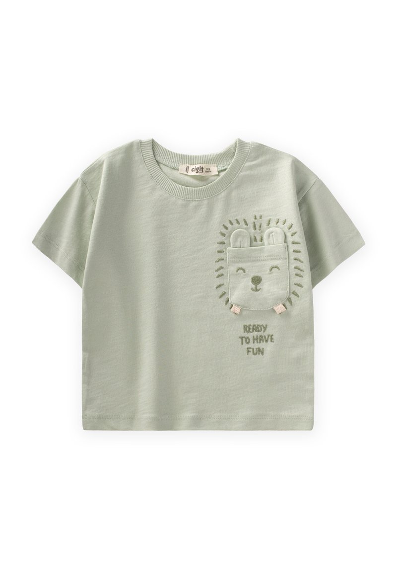 Camiseta de algodón verde claro con mangas cortas, que presenta un bolsillo bordado con la cara de un león y el texto "LISTO PARA DIVERTIRSE" debajo.