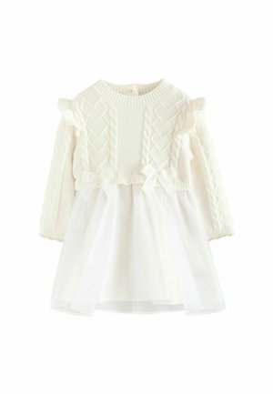 Weißes Kleid mit einem gestrickten Oberteil, das ein Zopfmuster aufweist, Rüschensäumen und einem mehrlagigen Tüllrock. Inklusive Taillenschleifen als Detail.