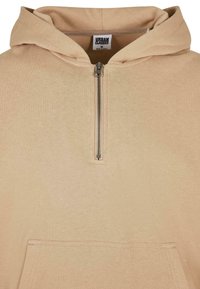 Felpa con cappuccio beige realizzata in tessuto morbido, con zip a metà davanti, grande tasca frontale e cappuccio regolabile con cordino.
