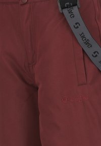 Pantaloni bordeaux in tessuto resistente con una trama liscia, dotati di chiusura con bottone visibile, tasche laterali e logo ricamato "ZIGZAG".