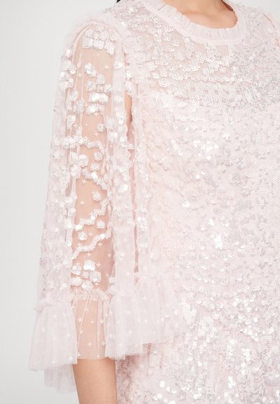 Rochie roz cu aplicații din paiete, mâneci bufante transparente și manșete cu volane. Țesătura are un aspect texturat datorită paietelor.