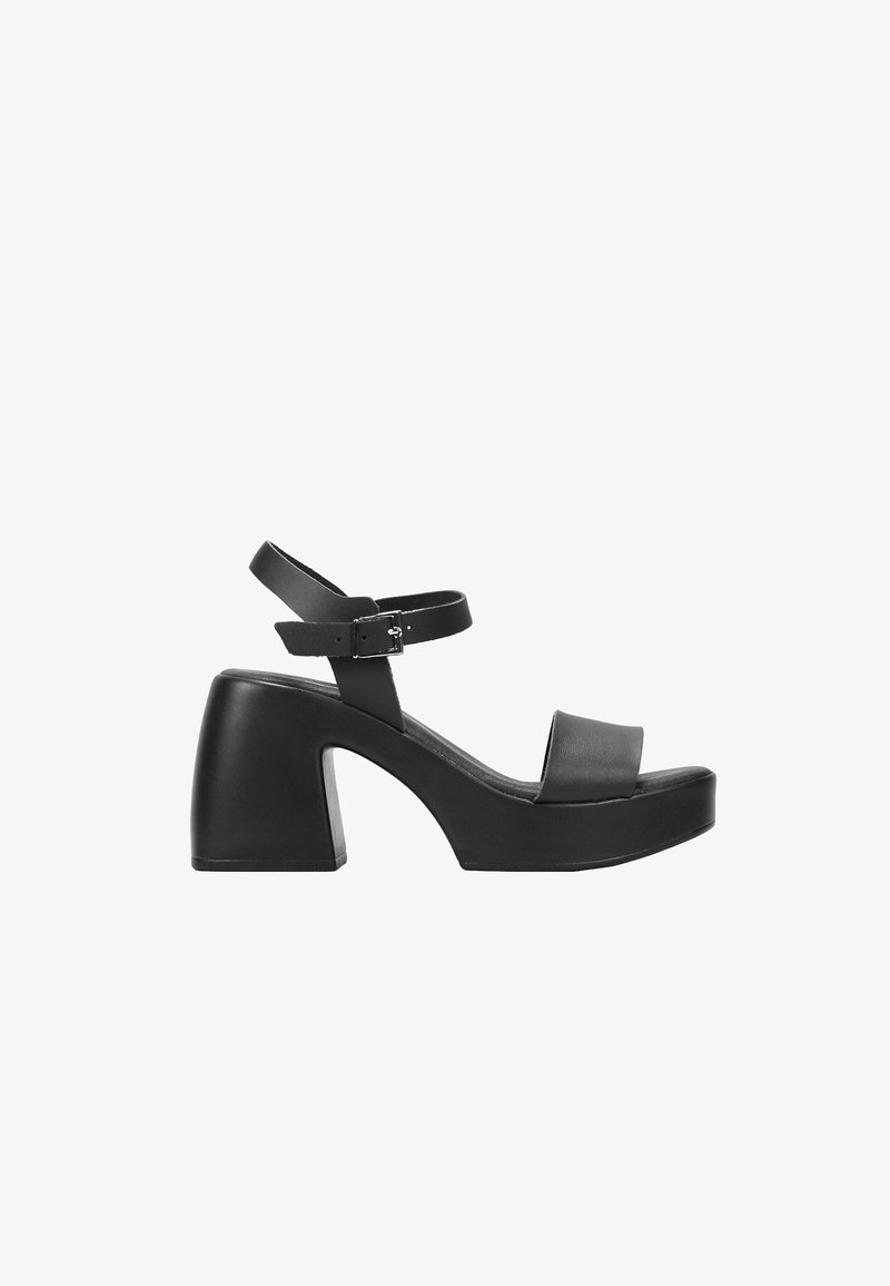 Sandalias negras de tacón alto con una plataforma gruesa, que presentan una amplia tira frontal y una tira de tobillo con un hebilla de metal. Acabado en cuero suave.