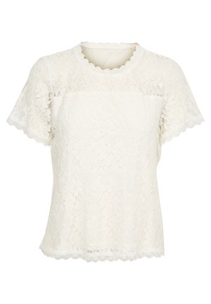 Haut en dentelle blanche avec des manches courtes à bords festonnés et un col lisse à bords festonnés. Motif floral délicat sur l'ensemble du tissu.