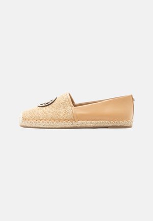 Μπεζ espadrille τύπου slip-on με πλεκτό μπροστινό μέρος, λείο δερμάτινο πίσω μέρος, ραφή ζιγκ-ζαγκ κατά μήκος της σόλας και στρογγυλό μαύρο έμβλημα στην κορυφή.