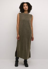 Robe longue sans manches en vert olive, fabriquée en matériau tricot doux. Présente des fentes sur les côtés et un ourlet côtelé pour plus de texture et de détails.