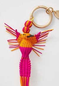 Un porte-clés coloré tissé présentant un design d'oiseau avec des fils roses, orange et jaunes. Attaché à un porte-clés en métal doré.