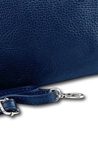 Donkerblauwe gestructureerde leren portemonnee met een zilveren hardware sluiting en een afneembare band, met een gladde afwerking en nette stiksels.