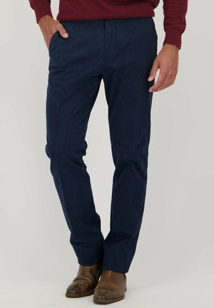 Chinos bleu marine en tissu lisse, dotés de deux poches avant et d'une coupe droite, associés à des bottes en cuir marron.