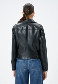 Svart läderjacka med en åtsittande design, som har en klassisk krage, synliga sömmar och dragkedjeärmar. Matchas med hög midja denimjeans.