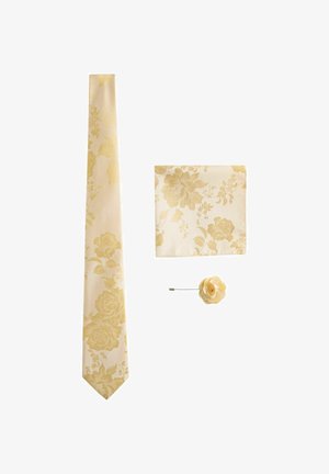 Cream necktie, matching pocket square, and small flower lapel pin, all with subtle gold floral pattern, arranged on white background.