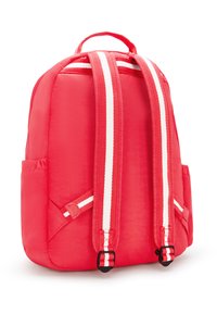 Červený nylonový batoh s dvojitými bílými pruhy na popruzích, vypolstrovaným zadním dílem, horním držadlem a bočními kapsami. Hladký povrch a zaoblený tvar.