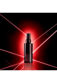 Bouteille spray noire à finition brillante, avec texte rouge et forme cylindrique, éclairée par des faisceaux laser rouges sur un fond sombre.