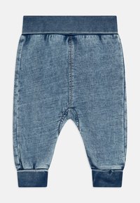 Pantaloni jogger in denim blu con cintura e polsini a coste. Caratterizzati da una texture morbida e cuciture tonali. La forma è un fit rilassato con stile a cavallo basso.