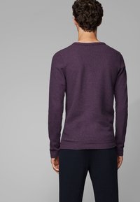 Långärmad tröja i mörklila bomullsmix. Rund halsringning och ribbade manschetter. Slät textur med en något figursydd silhuett.