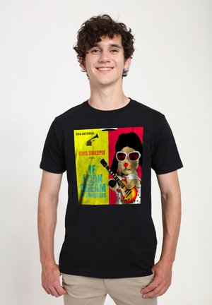 Sort t-shirt med et farverigt graphic af en tegneserie-bjørn med solbriller, der spiller guitar, med gule og røde baggrundselementer.