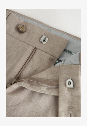 Gai brūni bikses ar teksturētu audumu. Tām ir ar rāvējslēdzēju aizvēršanās, pogu aizdare un metāla detaļas. Odere iekšpusē ir gaiši pelēka.