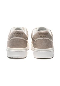 Zapatillas de ante beige con acentos blancos, que presentan una superficie texturada y un logo grabado en el talón. Punta redondeada y cuello acolchado.