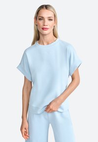 Light blue short-sleeve sweatshirt made of soft, smooth fabric. Features a round neckline and a relaxed fit, paired with matching pants.