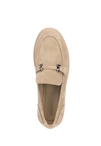 Mocasin de ante beige con punta redondeada, diseño deslizante y acentos decorativos en plata en la correa. Textura suave con suela de goma a contraste.