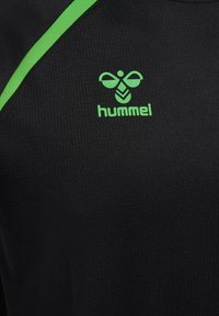 Tissu de sport noir avec logo d'abeille verte Hummel et texte, avec une bande diagonale verte sur le côté supérieur gauche.