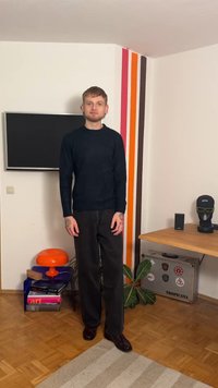 Navy knit sweater, black wide-leg trousers, and dark shoes. Features a minimalist design. Background includes a plant and decor elements.