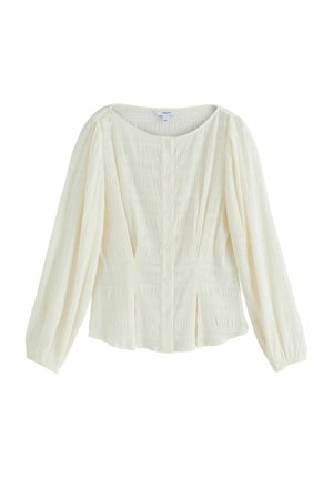 Kermanvärinen paita teksturoidusta kankaasta, pyöreä pääntie, edessä nappikiinnitys ja pitkät hihat kerätyillä kalvosimilla.