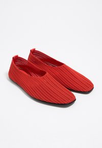 Rote Mesh-Slipper mit einer abgerundeten, flachen Zehenpartie und schwarzen Gummisohlen. Merkmal ist eine sichere Passform mit elastischen Rändern für Komfort und Atmungsaktivität.