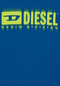 Camiseta de manga corta azul con un atrevido logo en degradado de neón amarillo "DIESEL DENIM DIVISION" en el centro. Material de algodón, textura suave.