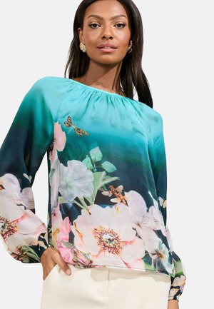 Blumenbluse in Türkis mit einem Verlaufseffekt, versehen mit großen rosa und weißen Blumen, Libellenakzenten und langen, gerafften Ärmeln.
