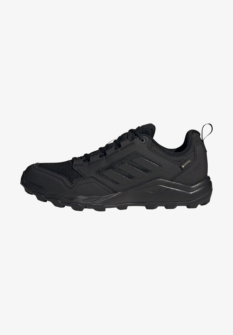 Baskets de sport noires avec tige en textile en mailles, semelle en caoutchouc et crampons d'adhérence. Comprend un design à trois bandes et une languette à l'arrière.