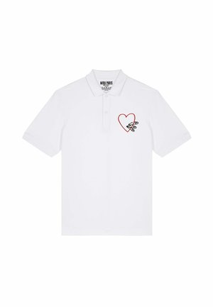 Polo blanc en coton, présentant un contour de cœur rouge avec un design d'épingles de sûreté sur la partie gauche de la poitrine. Manches courtes et col.