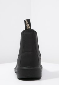 Botín negro de piel con un acabado suave, puntera redondeada, plantilla acolchada y un tirador de marca en la parte posterior. Suela de goma.