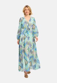 Robe longue et fluide avec un décolleté en V, une taille froncée et des manches longues. Présente un motif en zigzag bleu et vert sur un tissu léger.