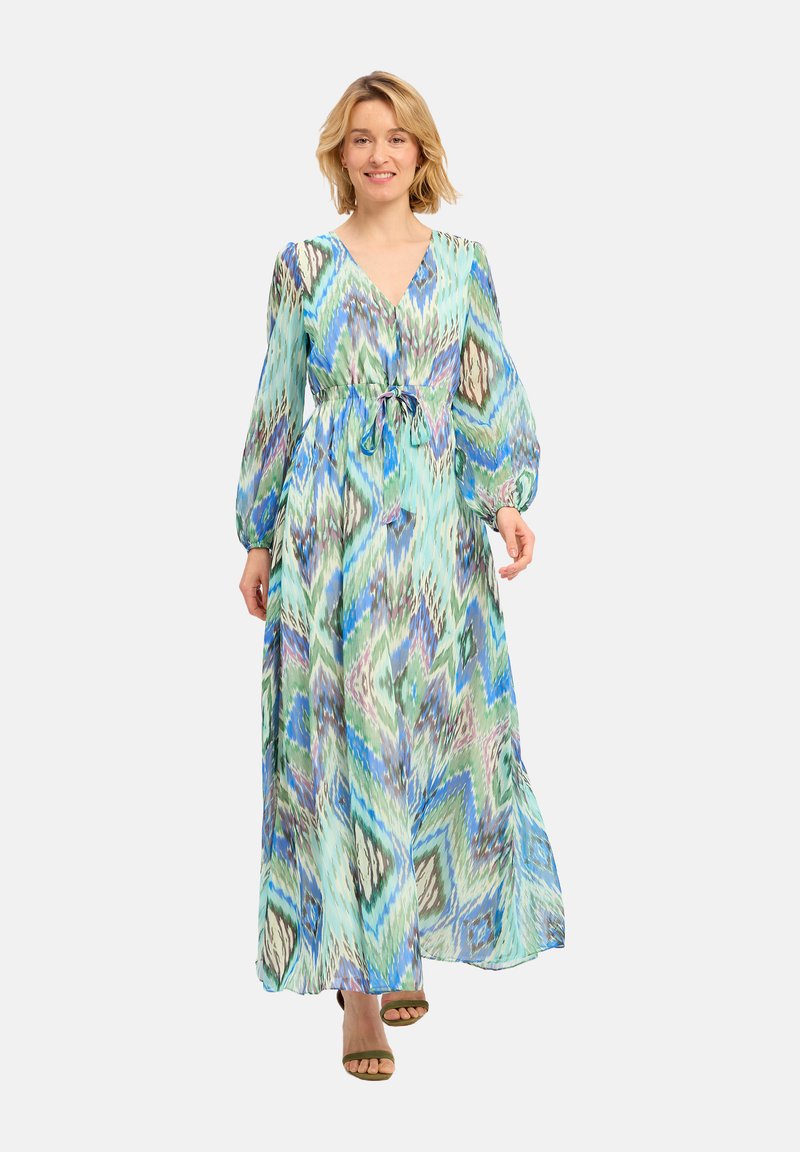 Robe longue et fluide avec un décolleté en V, une taille froncée et des manches longues. Présente un motif en zigzag bleu et vert sur un tissu léger.