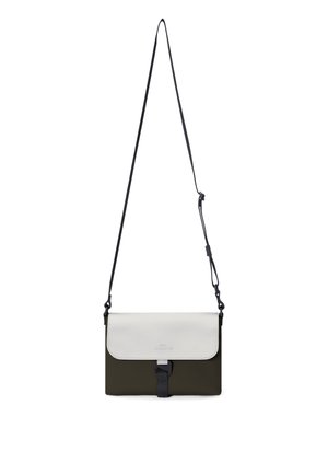Compact crossbody bag with white flap, black buckle, and olive green body, hanging by an adjustable black strap.