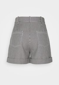 Bermuda a strisce bianche e nere con vita alta, risvolti e due tasche posteriori. Realizzata in tessuto leggero con cuciture a vista.