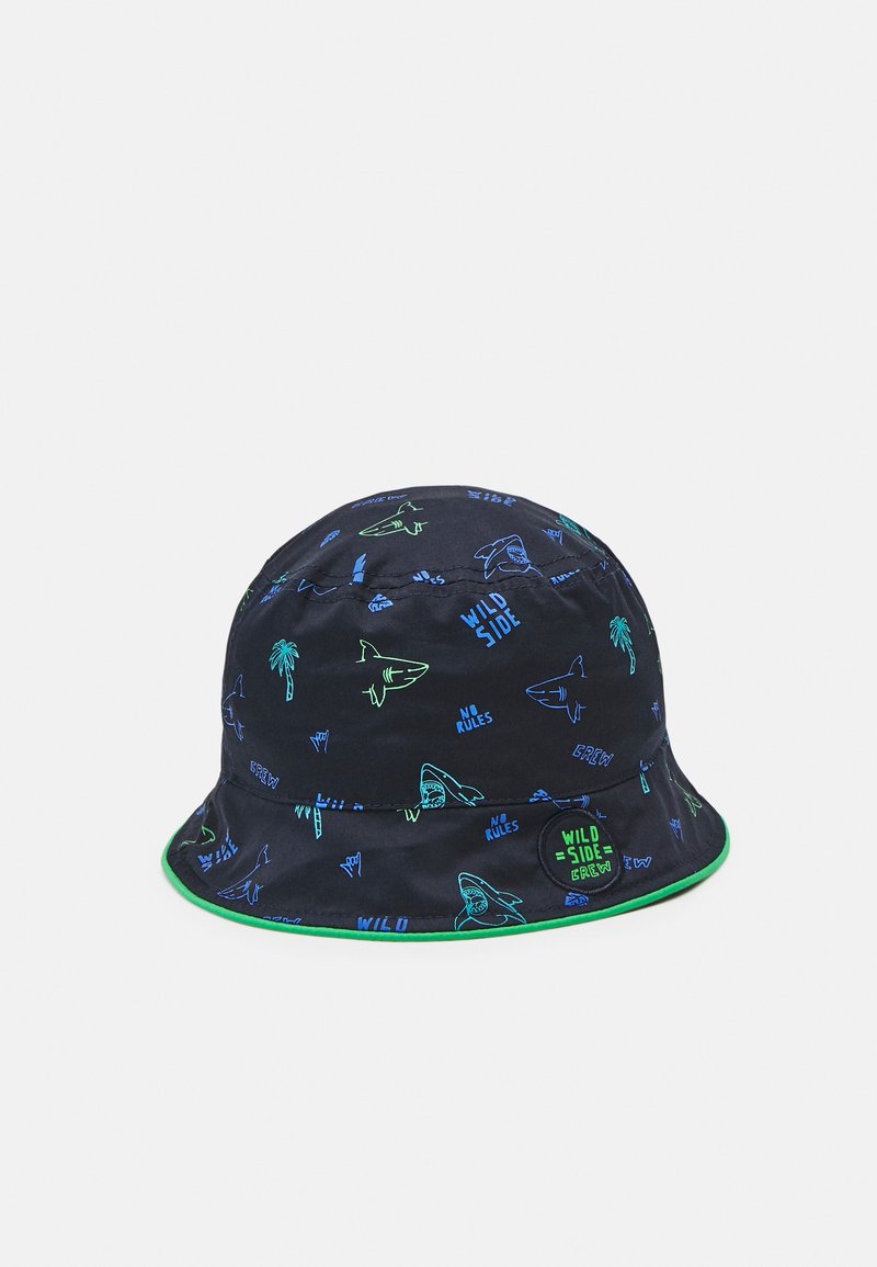 Marineblå bøttehatt med grønn brem, med livlige trykk av haier og palmer, samt tekstdesign som "WILD SIDE" og "NO RULES."
