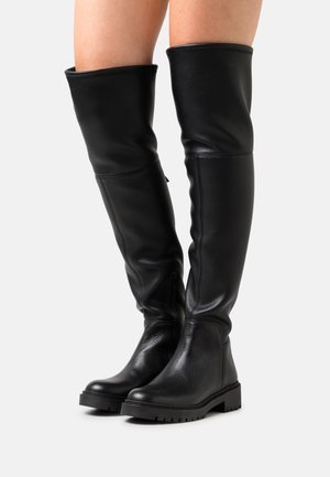 Bottines noires au-dessus du genou en cuir texturé, avec un bout rond, une semelle en caoutchouc plate et une fermeture éclair sur le côté pour un enfilage facile.